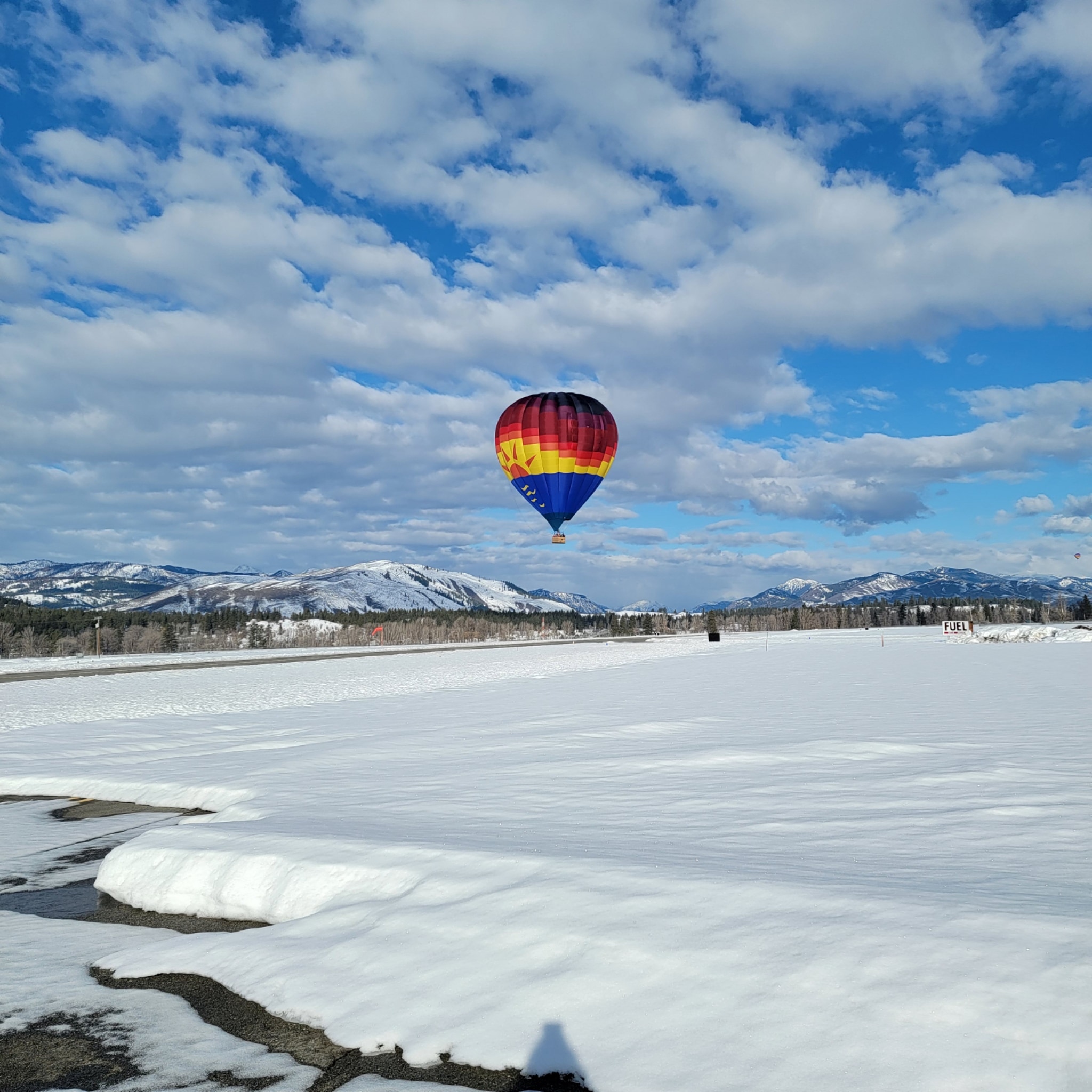 A brightly colored hot air balloon floating above a snow covered landscape.